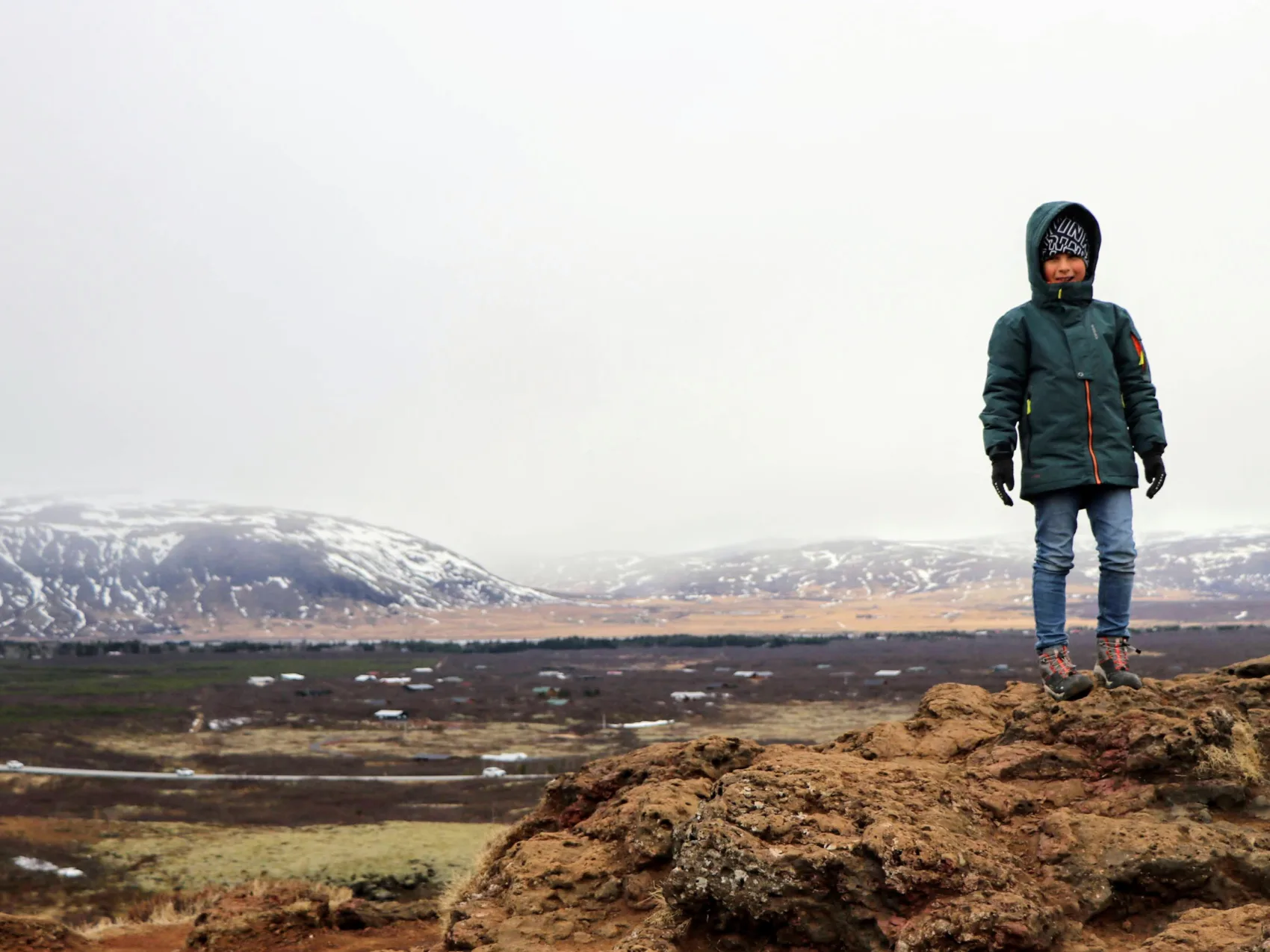 Kind auf einem Felsen in der Winterlandschaft Islands